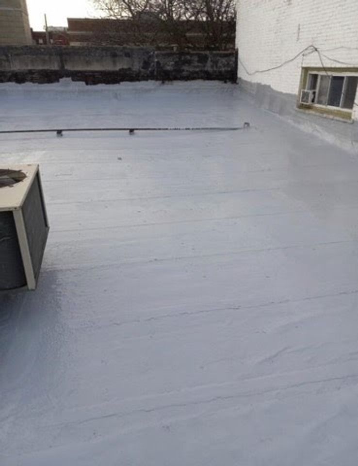 Silver-coated flat roof with a rooftop air-conditioning unit between brick buildings