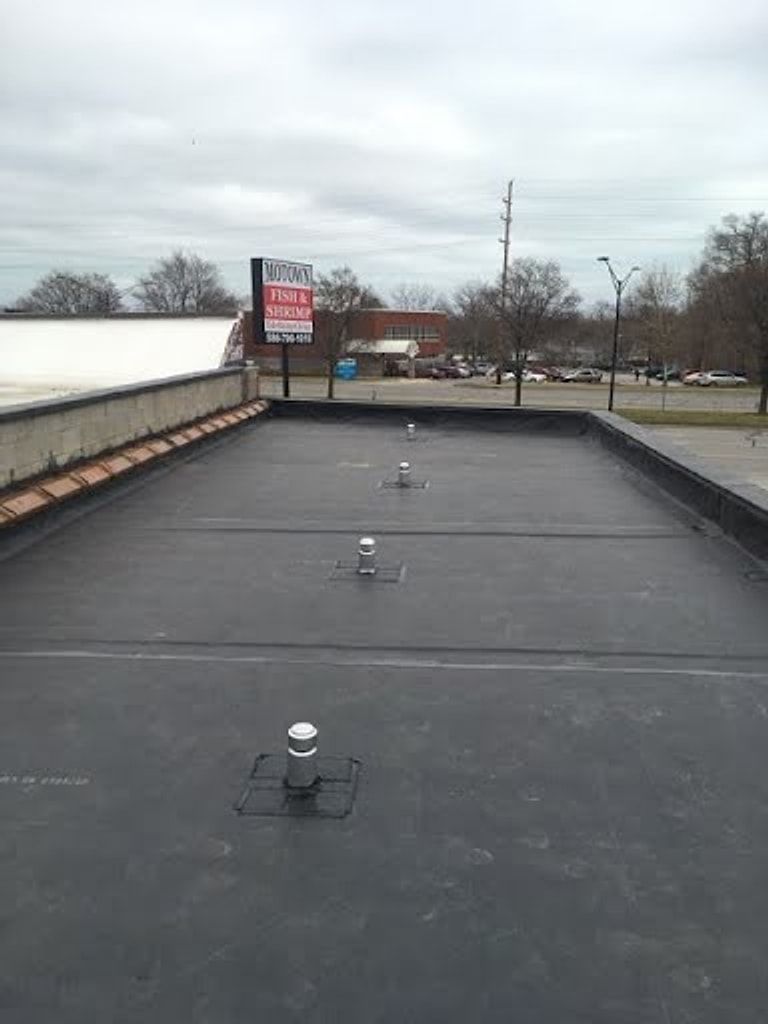 Black flat roof with parapet walls and pipe vents on a commercial building