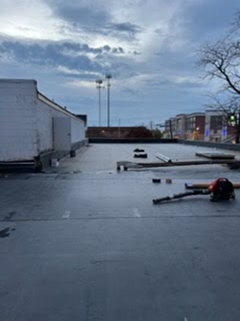 Tools and materials laid out for a flat roof repair between city buildings
