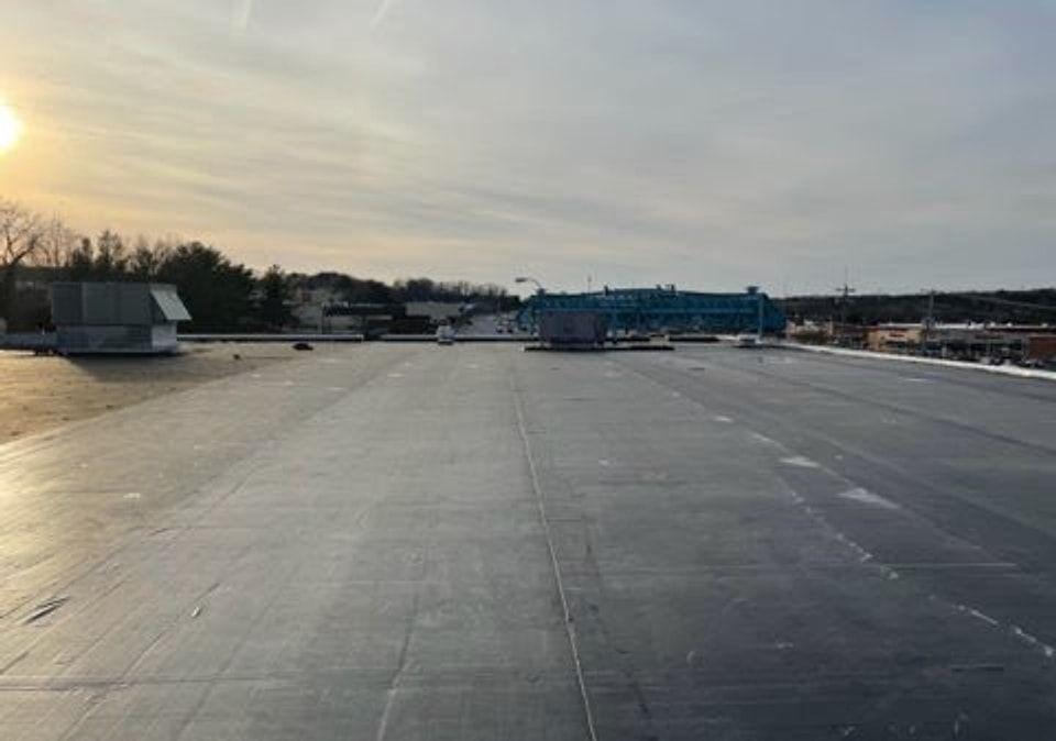 Wide black flat roof on a commercial building at sunset
