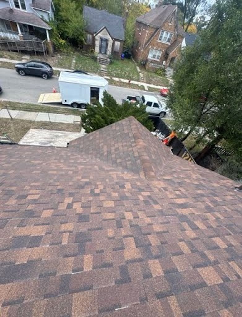 New brown architectural shingle roof seen from the ridge, with a residential street and houses below